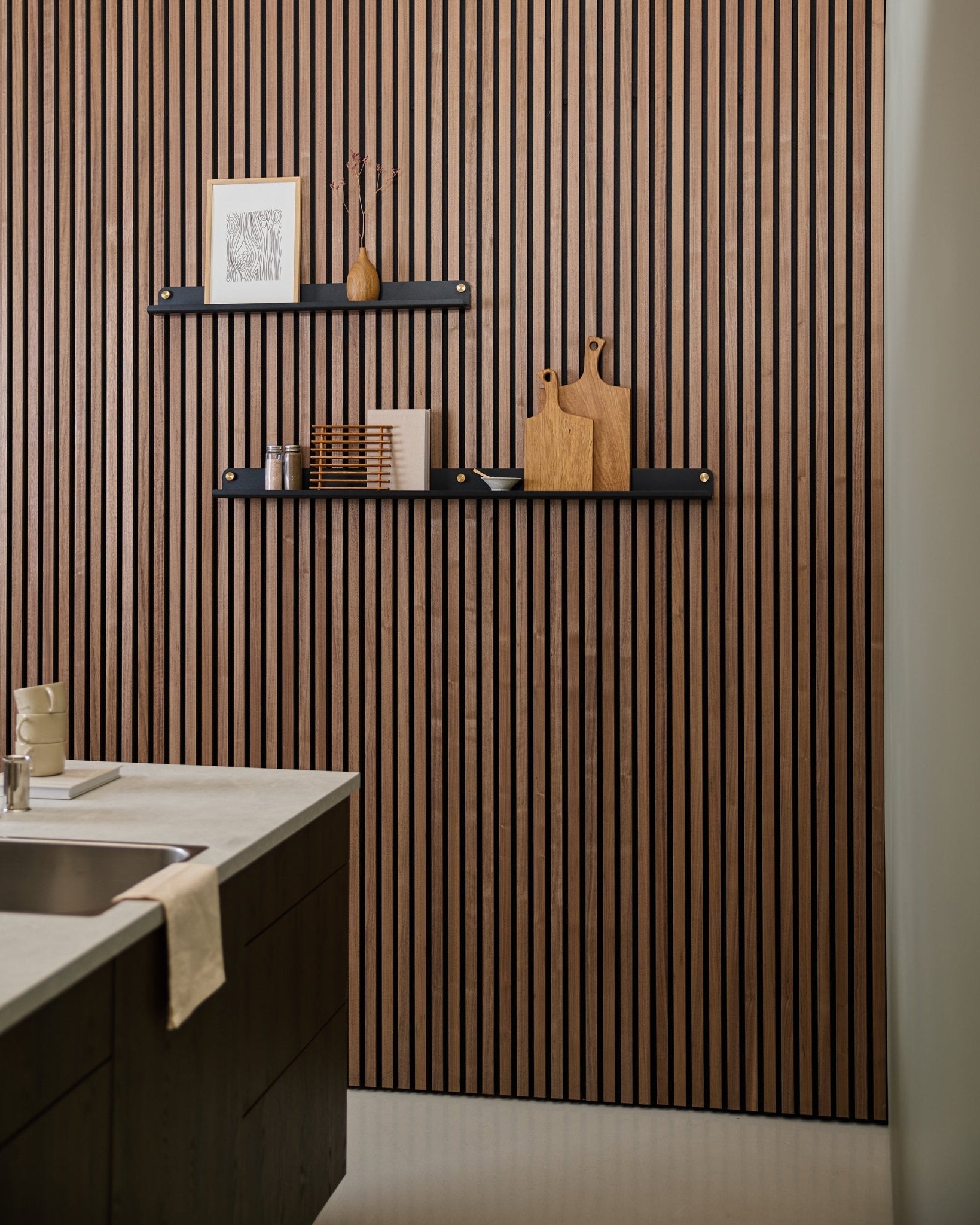 Cocina moderna con un panel acústico de lamas de estilo nórdico, una black WoodUpp Norr Narrow Estantería(115.9 cm) para decoración y una toalla colocada sobre el fregadero.
